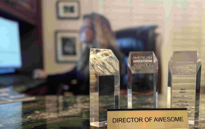 picture of denise grothouse founder of perfect six marketing at her desk with american advertising association awards