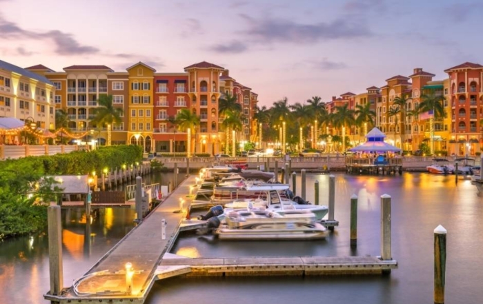 Boats, high-rise buildings in Naples, FL at sunset.