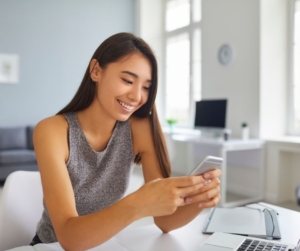 A woman with long dark hair reading an SMS message.