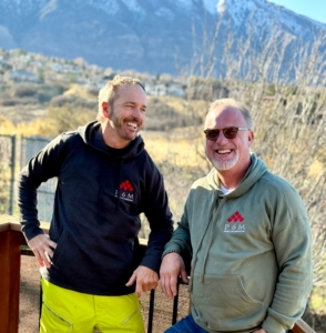 two men wearing near me custom logo hoodies standing by mountains