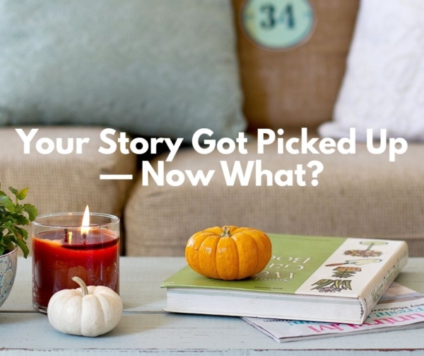Two small pumpkins and a candle on a table with magazines for PR.
