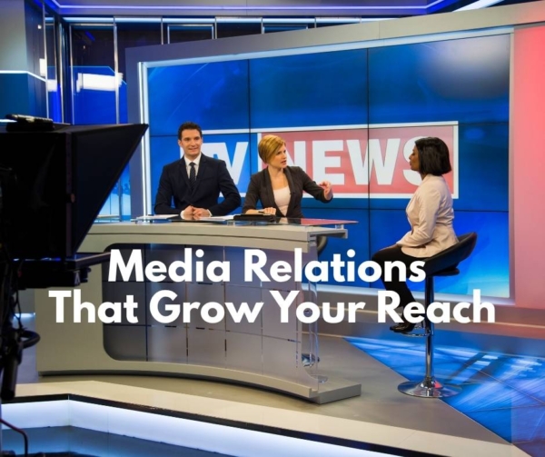 A TV newsdesk with 3 people. Blue background.